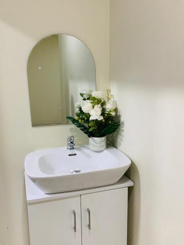 a bathroom sink with a mirror and a vase of flowers at Desaj in Accra