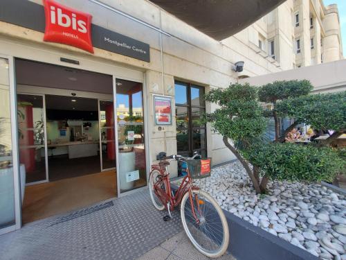 ibis Montpellier Centre Polygone في مونبلييه: دراجة حمراء متوقفة أمام متجر