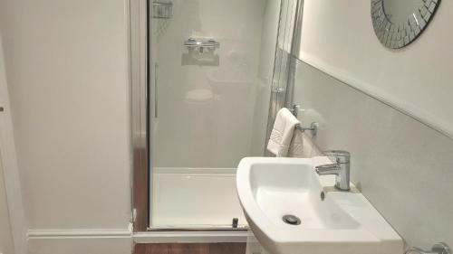 a white bathroom with a shower and a sink at The Trusty Servant Inn in Lyndhurst