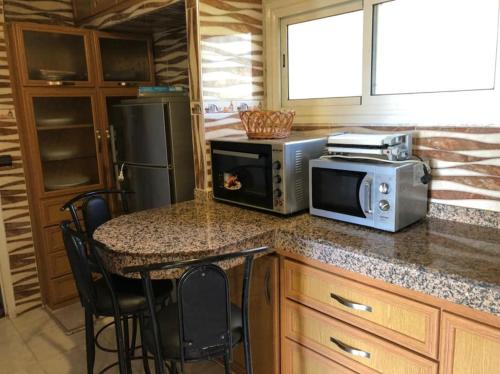 a kitchen with a counter with a microwave and a table at 100m² avec parking gratuit proche de la plage in Mohammedia