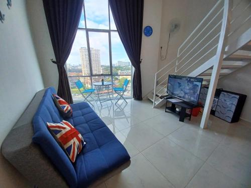 a living room with a blue couch and a large window at SY Staycation - Studio in Bayan Lepas