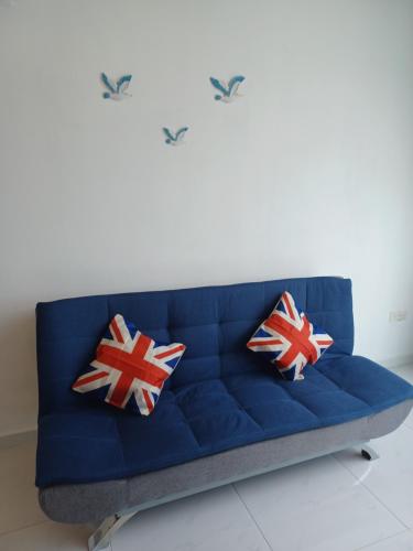 a blue couch with two pillows on it at SY Staycation - Studio in Bayan Lepas