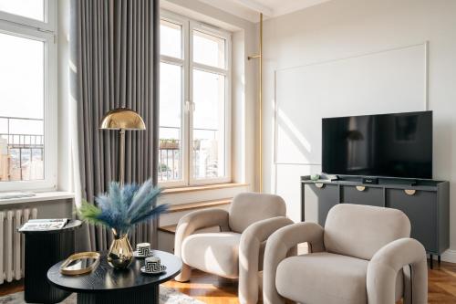 a living room with two chairs and a tv at Penthouse Panorama - LoftAffair in Kraków
