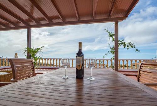 a bottle of wine sitting on a wooden table with two wine glasses at Villa Teram in Alajeró