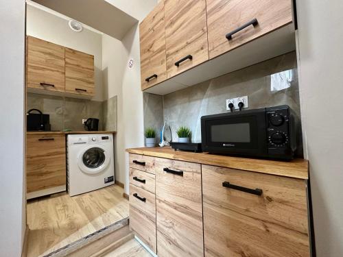 a kitchen with wooden cabinets and a microwave at MMRent Sparrow Room in Gdańsk