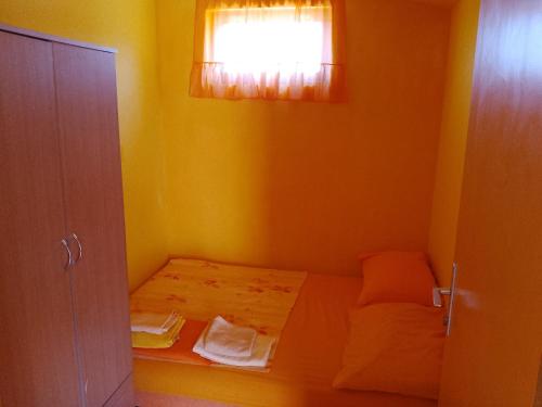 a small yellow room with a bed with a window at Apartments Velo in Veli Lošinj