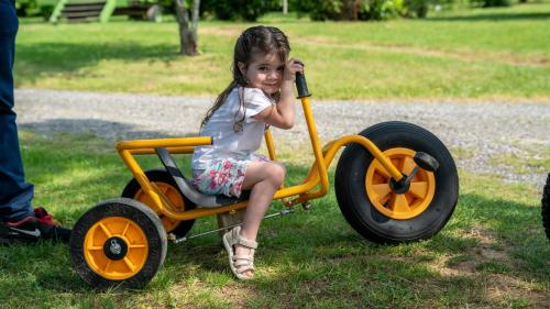 a little girl sitting in a toy car at Le Village de la Champagne - Slowmoov in Bar-sur-Aube
