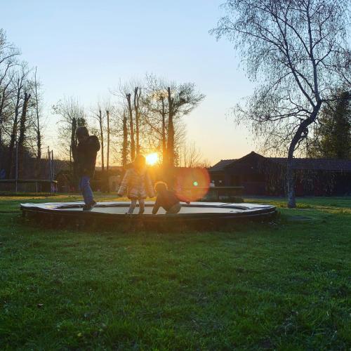a man and two children playing on a trampoline in the grass at Le Village de la Champagne - Slowmoov in Bar-sur-Aube