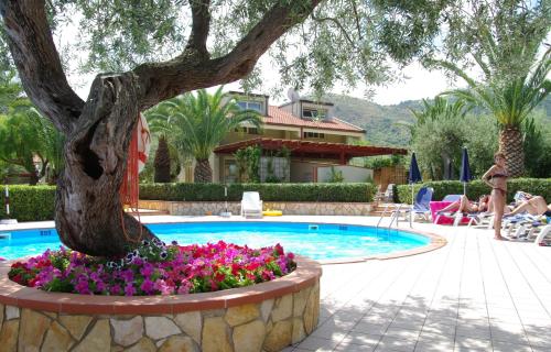 a swimming pool with a tree and flowers next to a house at Residence Fontana Barone in Cefalù