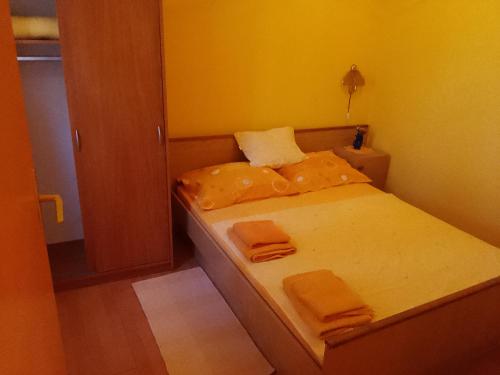 a small bedroom with a bed with orange sheets and towels at Apartments Velo in Veli Lošinj