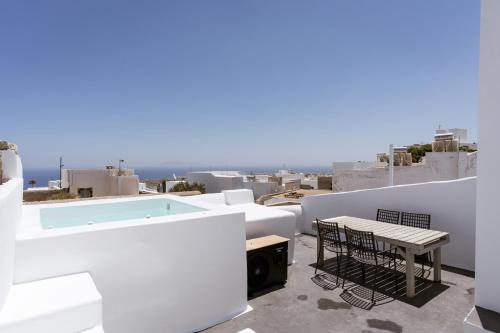 a balcony with a table and chairs and a swimming pool at On An Island suites & apartments - Fira in Fira