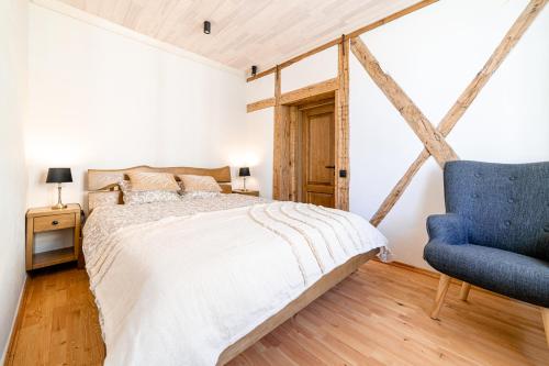 een slaapkamer met een bed en een blauwe stoel bij Boutique apartment Mezrozite in Kuldīga