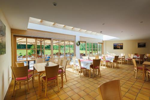 un comedor con mesas, sillas y ventanas en Alphotel Ettal, en Ettal