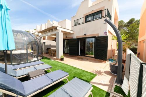 a backyard with lawn chairs and a house at Sunset sea view & garden Spa Cala Tarida 6p max in Cala Tarida
