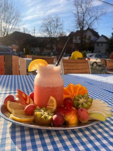 a plate of fruit and a drink on a table at Pensiunea 7 Tei in Cisnadioara