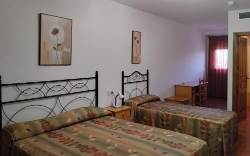 1 dormitorio con 2 camas, mesa y ventana en Hotel Condado de Miranda, en Miranda del Castañar