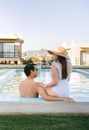 a man and a woman sitting next to a pool at Sol del Valle in Valle de Guadalupe