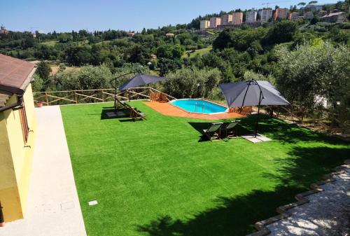 a green lawn with umbrellas and a swimming pool at IL VILLAGGIO DELLE FATE in Macerata