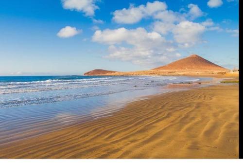 a sandy beach with a mountain in the background at LOFT Surf & Playa El Medano con WIFI Luminoso Ideal con Mascotas in El Médano