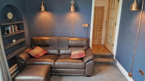 a living room with a brown leather couch with two pillows at Carr Garth in Arnside