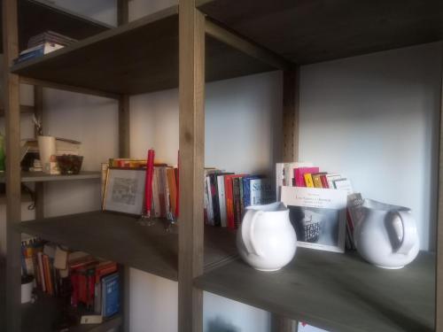 een boekenplank met vazen en boeken erop bij Appartamento di charme a Polverigi, Marche in Polverigi