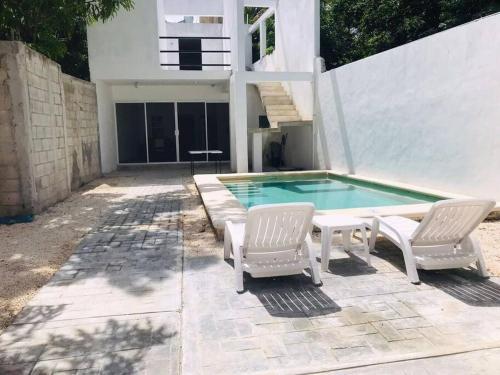 a swimming pool with two chairs and a table and a swimming pool at Casa vacacional Estrella in Cozumel