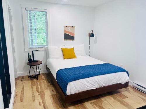a white bedroom with a bed with a yellow pillow at Bonnie View Inn in Haliburton