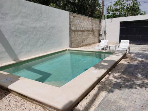 ein kleiner Swimmingpool mit zwei weißen Stühlen daneben in der Unterkunft Casa vacacional Estrella in Cozumel