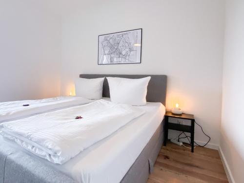 a bedroom with a large white bed with a night stand at Apartment mit Rheinblick, Messe, Balkon, Küche, Parkplatz in Neuss