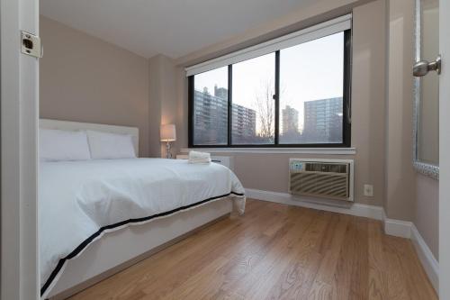 um quarto com uma cama e uma grande janela em Awesome 2 Bedroom Apartment in NYC em Nova Iorque