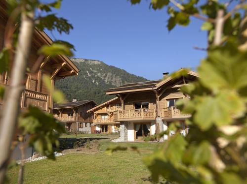 un groupe de bâtiments avec une montagne en arrière-plan dans l'établissement CGH Résidence Boutique Le Hameau De Pierre Blanche, aux Houches