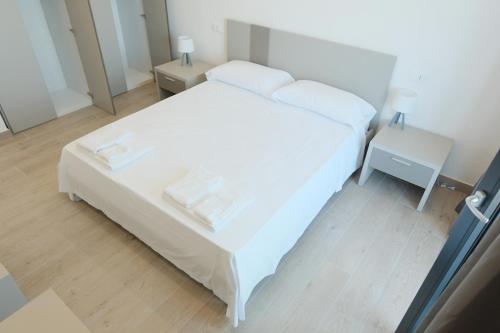 a small bedroom with a white bed and two tables at Like Lake Bisentina in Marta