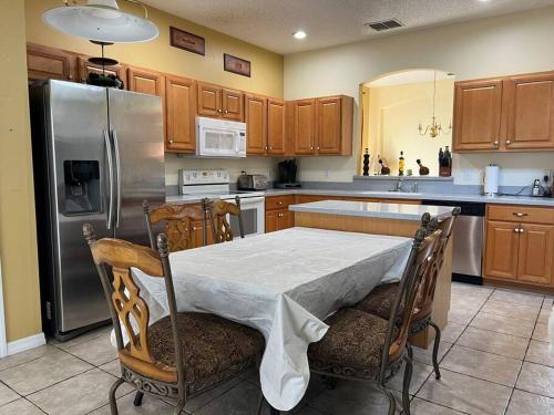 a kitchen with a table and a stainless steel refrigerator at Villa Madiera 6 bedroom huge house in Kissimmee