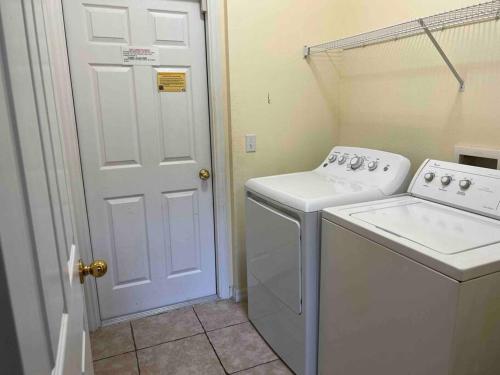 a laundry room with a washer and a white door at Villa Madiera 6 bedroom huge house in Kissimmee
