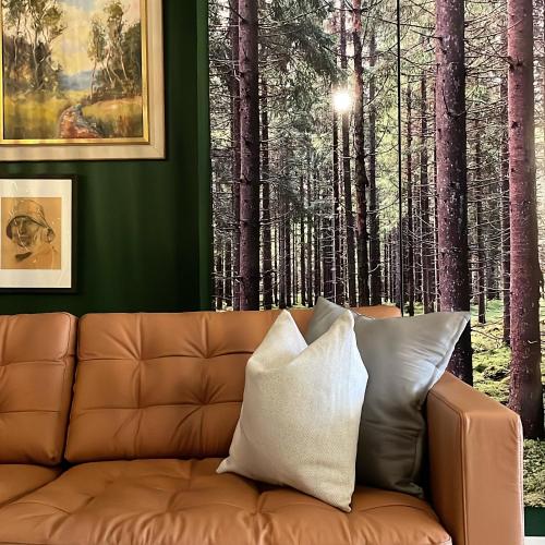 a couch in a living room with a forest mural at Hotell Nyboholm in Ulricehamn