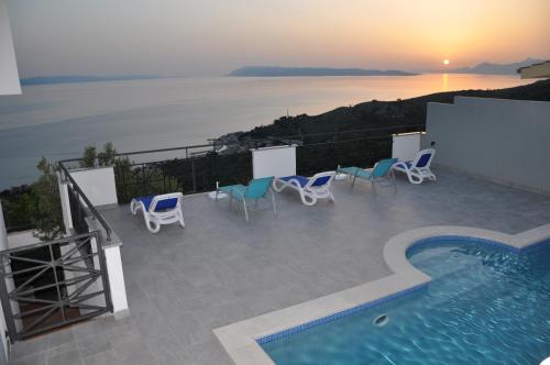 un patio avec des chaises et une piscine au coucher du soleil dans l'établissement Apartment natalia, à Podgora
