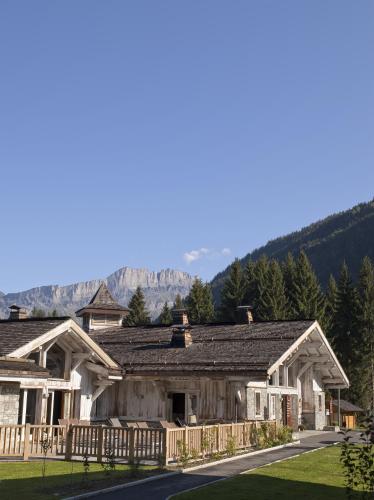 une maison en rondins avec des montagnes en arrière-plan dans l'établissement CGH Résidence Boutique Le Hameau De Pierre Blanche, aux Houches
