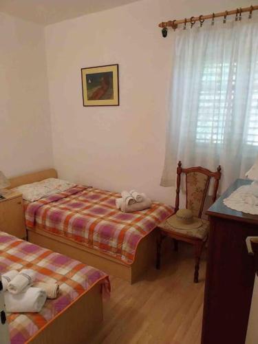 a small bedroom with two beds and a chair at Whole house Ariela, 20m to the beach, has a barbecue, 2 terraces in Šibenik