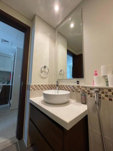 een badkamer met een wastafel en een grote spiegel bij Wonderful Reva Aparthotel Downtown in Dubai