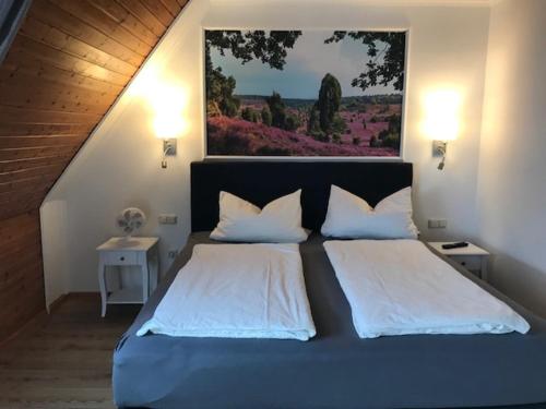 ein Schlafzimmer mit einem großen Bett und einem Gemälde an der Wand in der Unterkunft Naturhotel Hof Ehlers in Bergen