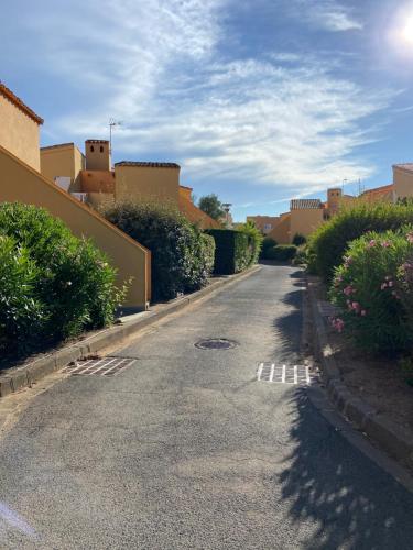 une rue vide avec quelques buissons et bâtiments dans l'établissement Résidence les 4 soleils, au Cap d'Agde