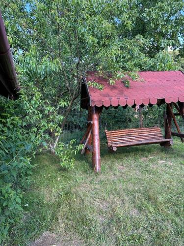 a bench in a park with a red roof at Cristian in Dejani