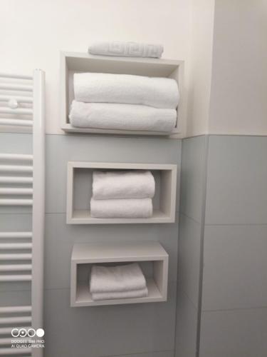 a bathroom with white towels on shelves at Civico 6 in Peschiera del Garda