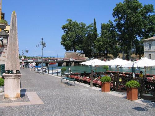 a walkway with tables and umbrellas next to a river at Civico 6 in Peschiera del Garda