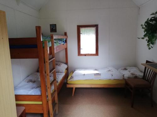a room with two bunk beds and a window at Kemp a Loděnice Podolsko - Chatka pro 3 osoby 