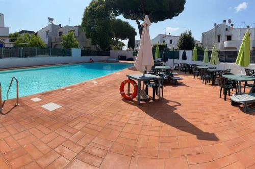 uma piscina com mesas e guarda-sóis e cadeiras ao lado de uma piscina em Villa Esperanza em Marina di Cerveteri