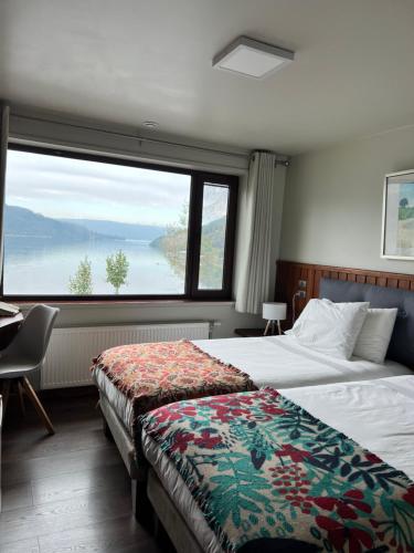 Habitación de hotel con 2 camas y ventana grande. en Hotel Boutique Cutipay en Valdivia