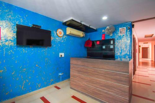 a room with a blue wall and a tv at OYO Flagship Karnal Royal in Karnal