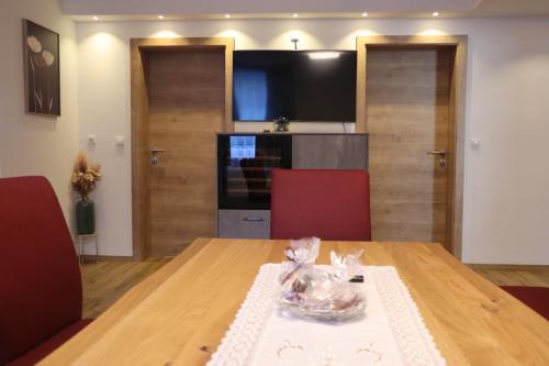 a dining room table with two red chairs and a television at Landhaus-Appartements Warraich in Schladming