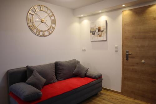 a living room with a couch and a clock on the wall at Landhaus-Appartements Warraich in Schladming
